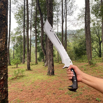 Person holding a large machete knife in a forest setting for camping and protection
